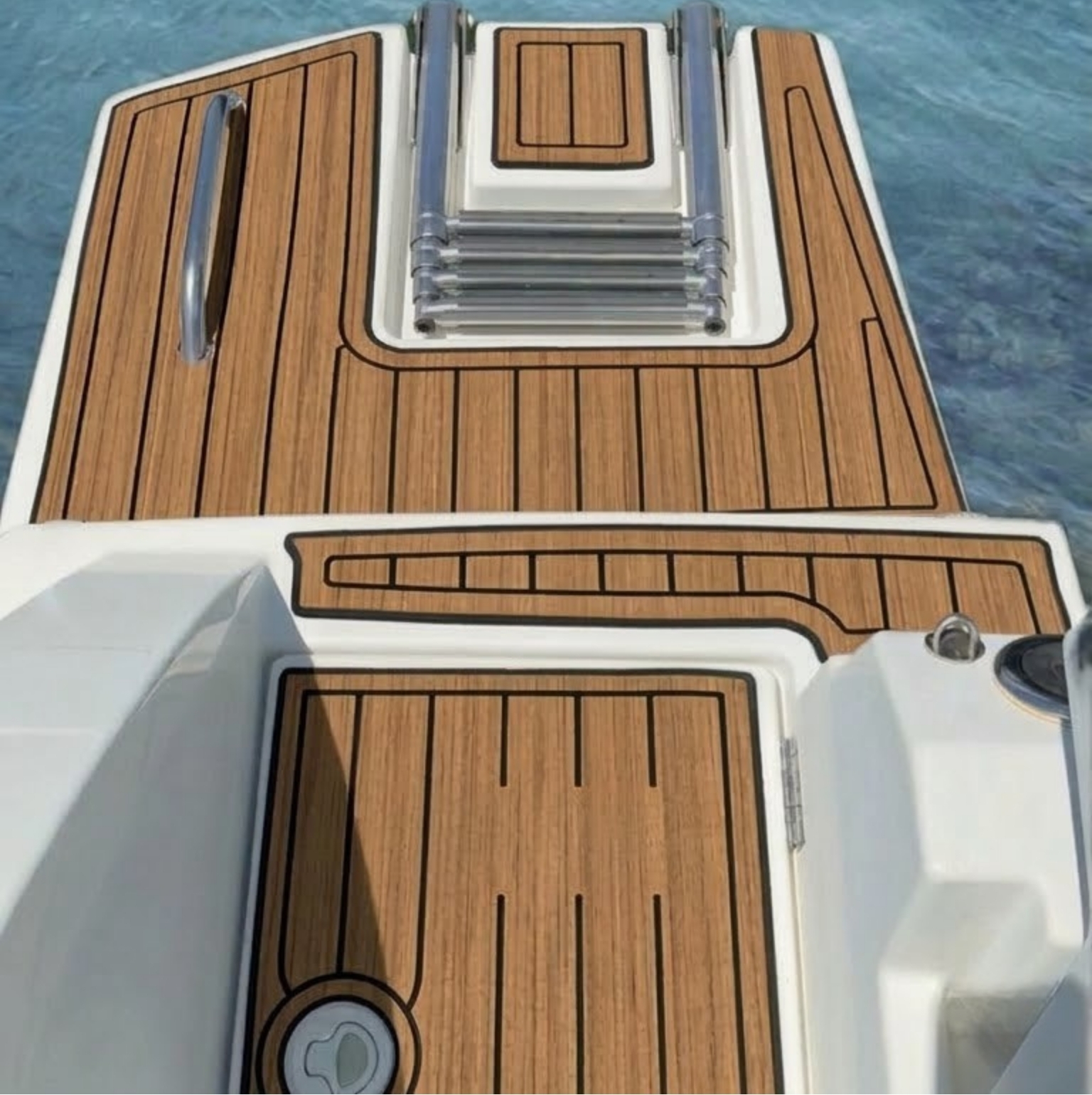 Aerial view of a boat deck fully covered with custom-cut EVA teak decking sheet, including cockpit floor, swim platform, and helm seat base sections