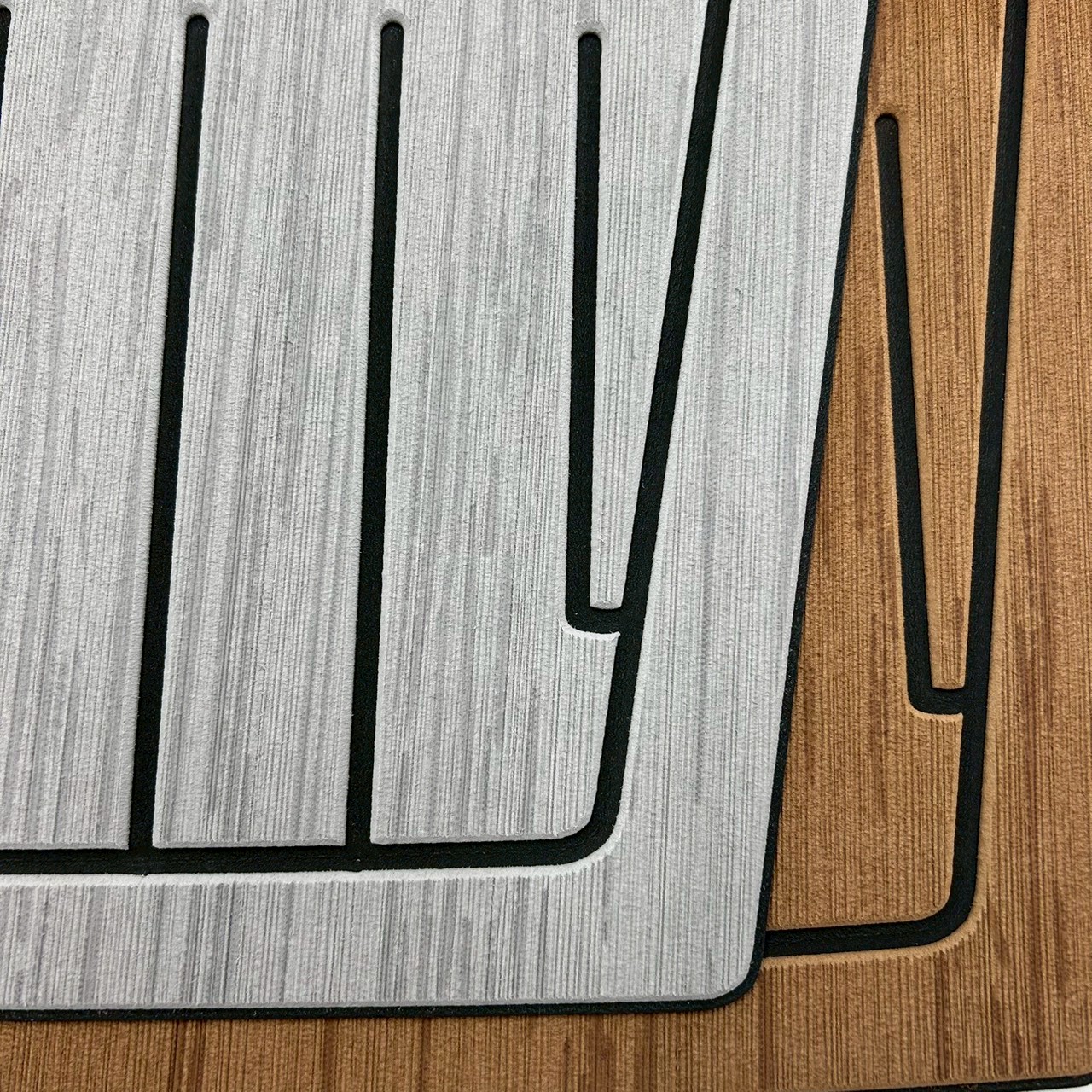 Close-up corner view of EVA faux teak decking sheet showing engraved grain lines, caulking seams, and color-matched edge finishing